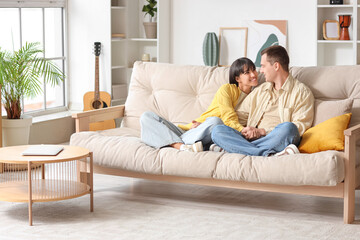 Poster - Young couple in love hugging on sofa at home