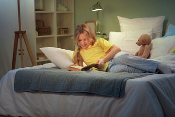 Wall Mural - Adorable girl reading fairy tale before sleep in bed