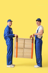 Sticker - Loaders using cargo belts for carrying chest of drawers on yellow background