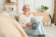 © Pixel-Shot - Middle-aged woman with laptop lying on sofa at home