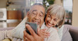 © peopleimages.com - Elderly couple, selfie and smile in lounge, hug and together in house, online and photography for memory. Home, profile picture and old man with woman, happiness and app in mobile and love in post