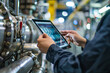 © Firn - Hands holding smart industry control tablet with blurry machine in background