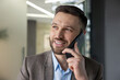 © Liubomir - A confident businessman with a beard talking on his smartphone in a modern office setting, smiling while engaging in a conversation.