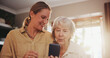 © peopleimages.com - Senior, mother and woman with phone in home with helping for social media, online games and bingo app. Family, elderly person and discussion with smartphone for explaining, learning or happy in house