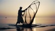 © abu - silhouette of  A traditional fisherman casting a net into the ocean at dawn