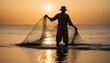 © abu - silhouette of  A traditional fisherman casting a net into the ocean at dawn