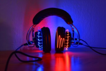 Sticker - Neon headphones with sound waves, dark background, vibrant red and blue hues, futuristic and energetic digital art 