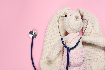 Canvas Print - Toy bunny and stethoscope on pink background, top view. Space for text