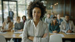 © VK Studio - An assured woman in a blazer stands confidently with crossed arms in front of an engaged audience in a spacious and bright seminar room.
