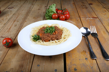 Wall Mural - Spaghetti served with fresh tomatoes and greens on a plate