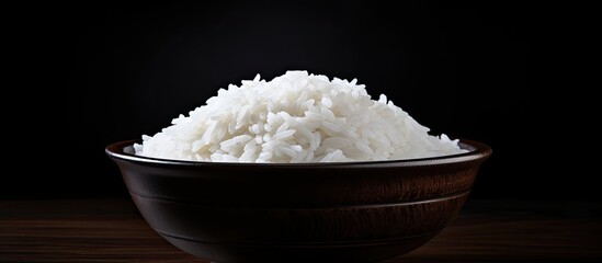 Poster - Bowl of white rice with ear on dark black table copy space image