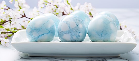 Aufkleber - Tray of blue Easter eggs transformed into dyed eggs with a light blue marble effect Placed on a white tablecloth adorned with cherry blossoms Provides a serene background with copy space for an Easte
