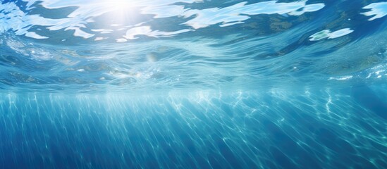 Poster - The transparent blue water has a sun glare creating a captivating wave texture background perfect for a copy space image