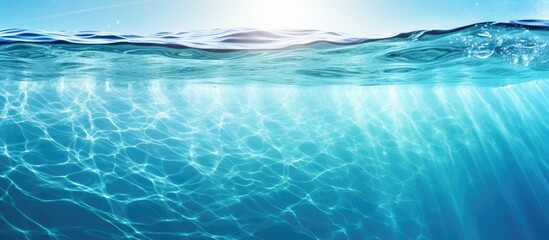 Poster - The transparent blue water has a sun glare creating a captivating wave texture background perfect for a copy space image