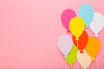 Wall Mural - Colorful balloon shapes from application paper with white strings on light pink table background. Pastel color. Closeup. Empty place for inspirational text, quote or sayings. Top down view.