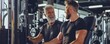 © Mark - A senior man does strength workout exercises in a gym with a young trainer.