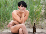 Nude woman on the seashore sitting on a wooden bench