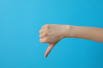 Wall Mural - Female hand showing finger down on blue background