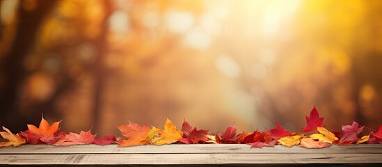 Poster - Autumn-themed wooden table with a blurred red and yellow leaves background sets the scene for a copy space image.
