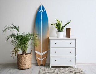 Poster - Surfboard, houseplant and chest of drawers near white wall in room