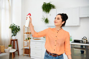 a stylish woman in casual attire holding a red and white object, possibly cleaning her home.