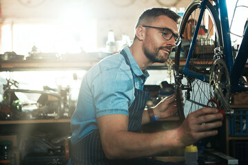 Wall Mural - Man, garage and serious as bicycle mechanic with lens flare in startup or small business. Workshop, tools and confident as handyman with fixing bike at repair or maintenance shop as entrepreneur