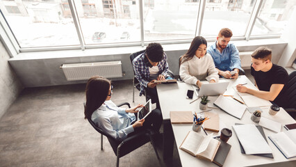 Aufkleber - Several professionals are gathered around a rectangular table in an office, engaged in a discussion. Papers, laptops, and pens are scattered on the table, view above, copy space