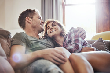 Poster - Happy, couple and hug on sofa with laughing at home for funny joke, humor and romance in relationship. Peace, man and woman with smile in living room for joy, comfort and bonding together on weekend