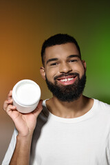 Wall Mural - Handsome young man with a beard holding a container of cream.