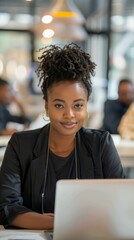Poster - A woman with a black jacket and a ponytail is sitting at a table with a laptop