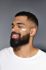 Wall Mural - African american handsome man with a beard showcasing white cream on his face.