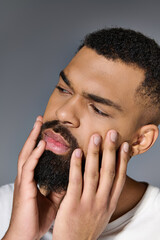 Wall Mural - Handsome young man in white t-shirt tending to his beard.