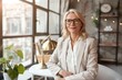 © Anastasia - Smiling mid-aged woman in white suit and glasses sitting confidently in modern office