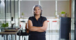 © Raushan_films - Indian Asian older aged adult boss ceo woman lady agent cross arms look cam do pose head shot video elder old gen x female worker staff expert standing proud fold hand indoor job office work place day