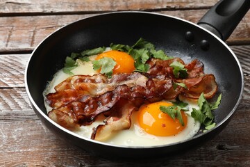 Wall Mural - Tasty bacon, eggs and parsley in frying pan on wooden table, closeup