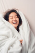 © Enrique - happy smiling asian woman in light white plain blanket
