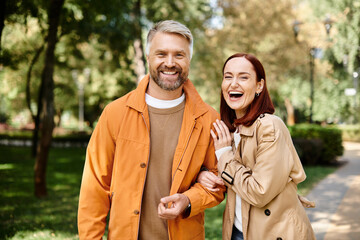 A man and a woman in casual attire walk together in a tranquil park setting.