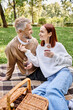 © LIGHTFIELD STUDIOS - A man and woman sit on a blanket in a park, holding wine glasses.