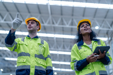 Male and female engineers in neat work clothes prepare and control the production system of large modern machines in a factory producing industrial technology products.