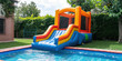 © IndigoElf - Inflatable bounce house with slide to the water pool in the backyard