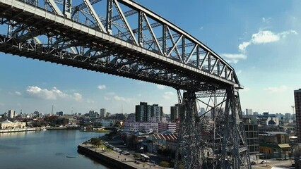 Wall Mural - La Boca ferry bridge on the riachuelo and panoramic view of Buenos Aires, Argentina. Aerial camera rises from the bridge and shows the city