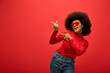 © LIGHTFIELD STUDIOS - Stylish African American woman striking a pose in trendy red shirt and sunglasses.