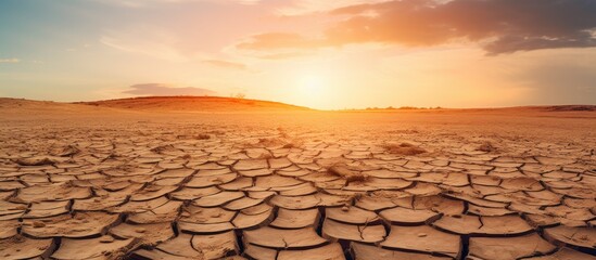 Poster - Barren dry terrain under a setting sun, portraying the harsh effects of drought and desertification. with copy space image. Place for adding text or design