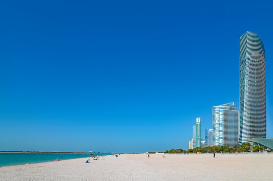 Panoramic landscape with sea, sandy beach and skyscrapers during sunny day in Abu Dhabi,  United Arab Emirates