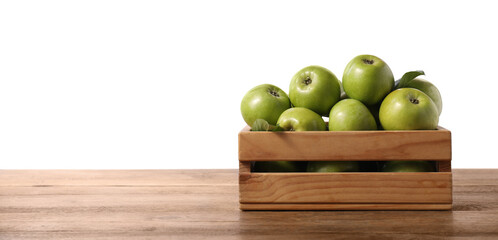 Wall Mural - Ripe green apples in crate on wooden table against white background. Space for text