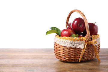 Wall Mural - Fresh ripe red apples in wicker basket on wooden table against white background. Space for text