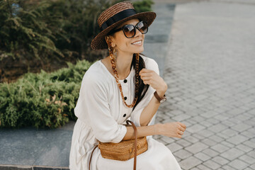 Wall Mural - beautiful woman walking in street on vacation dressed in white summer fashion dress