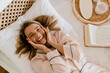 © mary_markevich - pretty smiling woman relaxing at home on bed in morning in pajamas