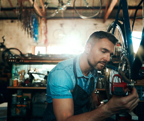 Wall Mural - Bicycle technician, repair and working in shop with tyre, chain and tools for maintenance or cycling. Man, mechanic and bike in workshop as handyman for gear, inspection and safety with service