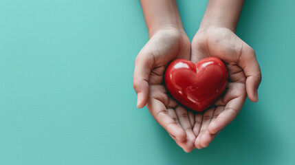 A person is holding a red heart in their hands